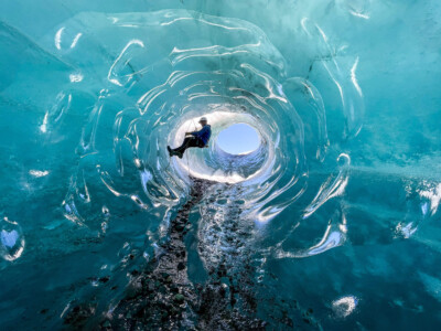man climbing the walls of an ice cave